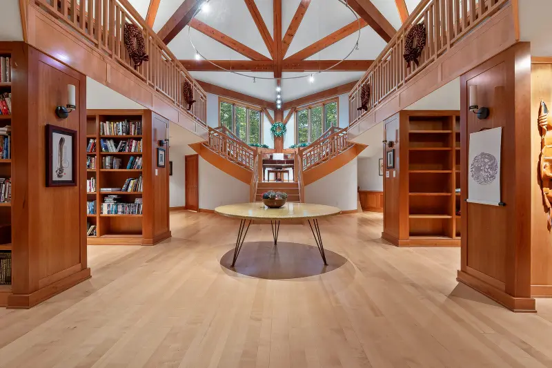 Timber-frame great room with built-in bookshelves and a grand staircase in a Northeastern Pennsylvania home